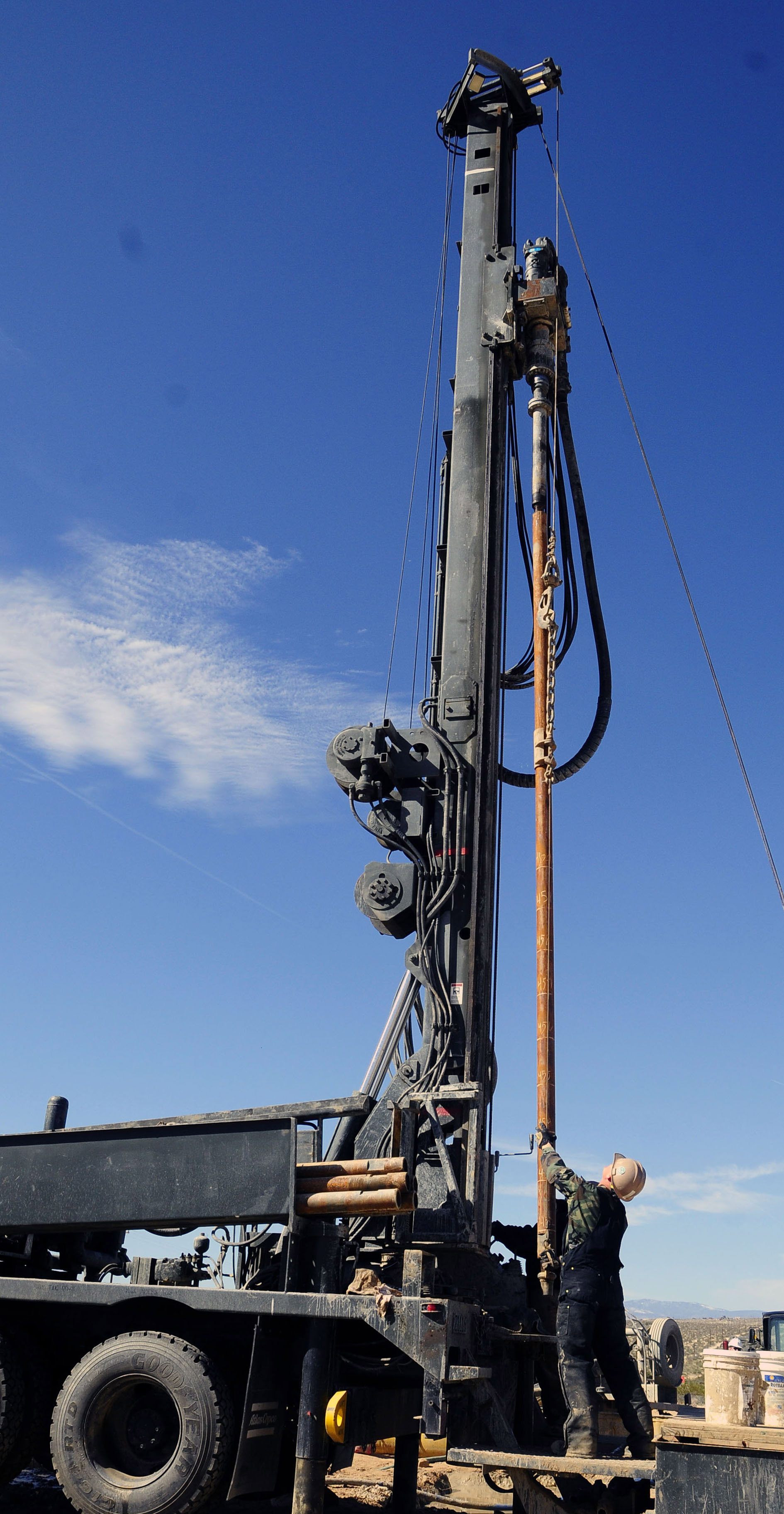 A water well drilling rig with drill steel raised, and a driller working at the deck